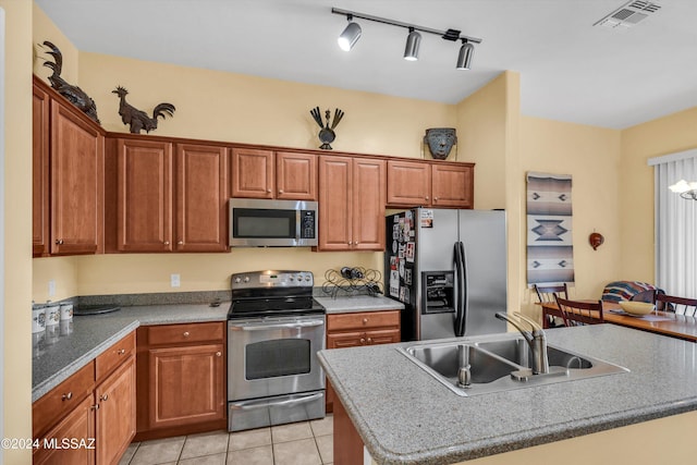 kitchen with appliances with stainless steel finishes, an island with sink, light tile patterned flooring, and sink