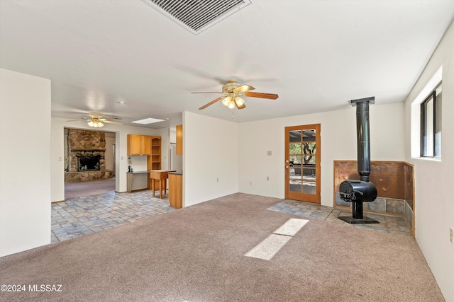 unfurnished living room featuring a wealth of natural light, ceiling fan, and light carpet