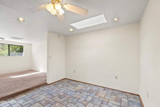 spare room featuring a skylight and ceiling fan