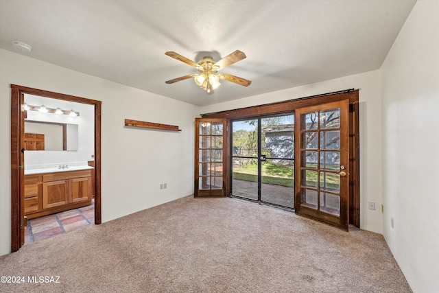 carpeted empty room featuring french doors, ceiling fan, and sink