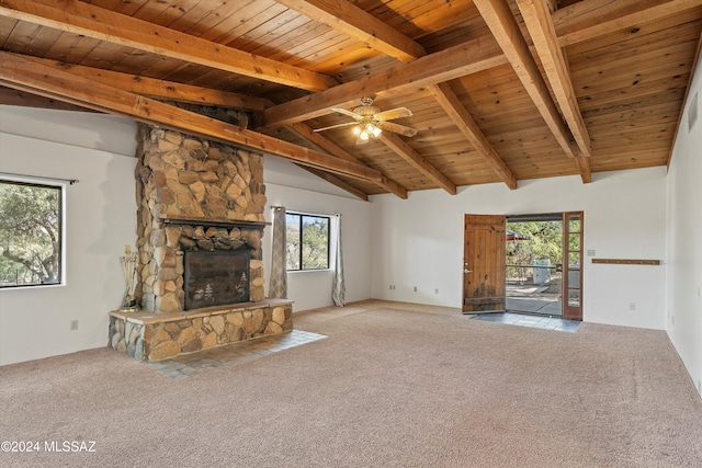 unfurnished living room with carpet flooring, vaulted ceiling with beams, a stone fireplace, and wood ceiling