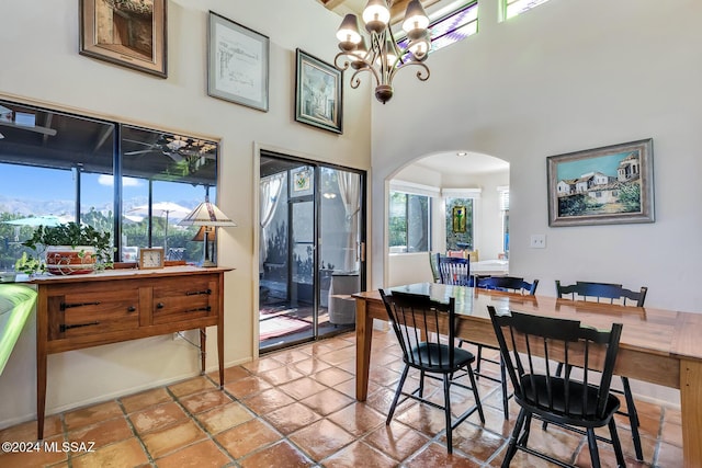 tiled dining room featuring a notable chandelier and a towering ceiling