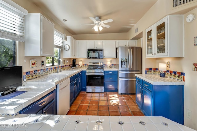 kitchen with pendant lighting, stainless steel appliances, white cabinets, and blue cabinets