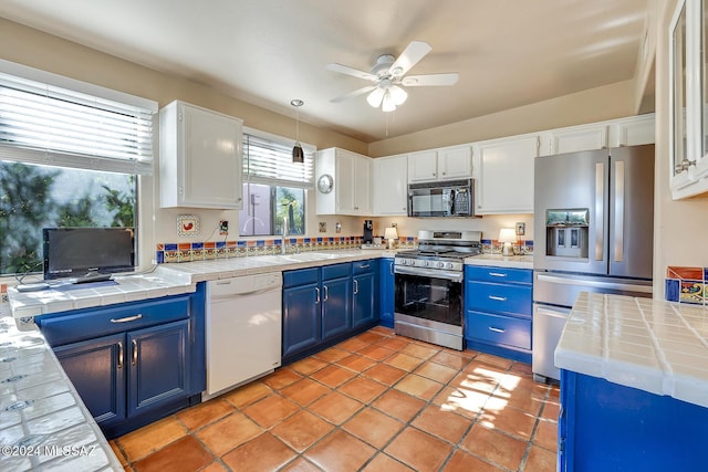 kitchen featuring tile counters, stainless steel appliances, white cabinets, and blue cabinets