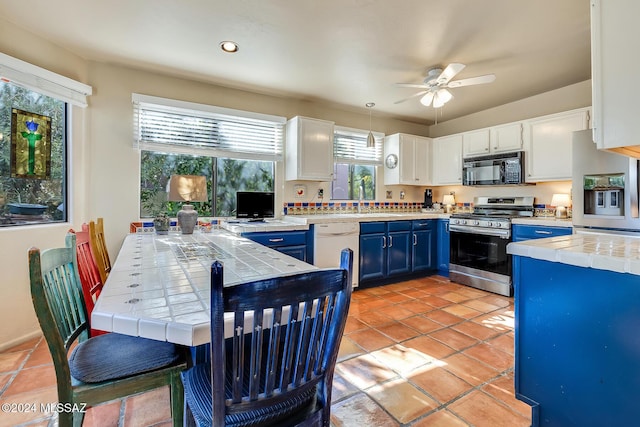 kitchen with tile countertops, decorative light fixtures, blue cabinets, white cabinets, and stainless steel appliances