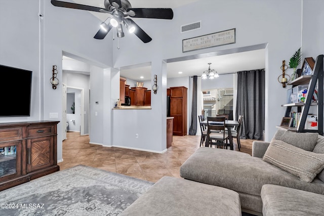 living room featuring a high ceiling, light tile patterned floors, and ceiling fan with notable chandelier