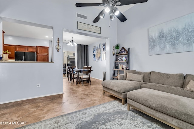 living room with a towering ceiling, light tile patterned flooring, and ceiling fan with notable chandelier