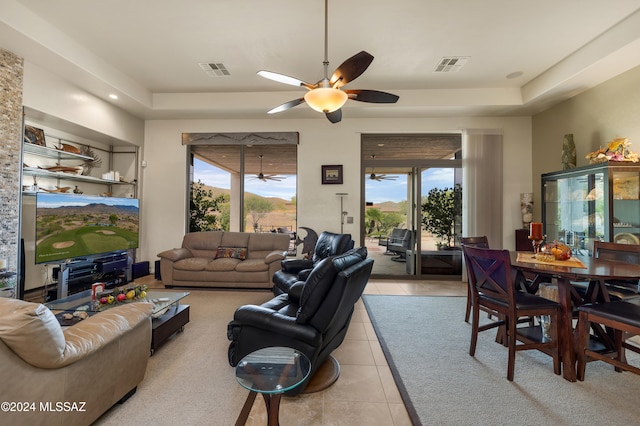 tiled living room featuring ceiling fan and a tray ceiling