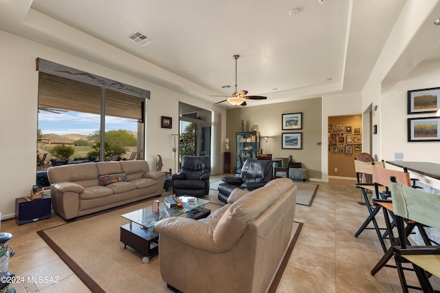 tiled living room featuring ceiling fan and a raised ceiling