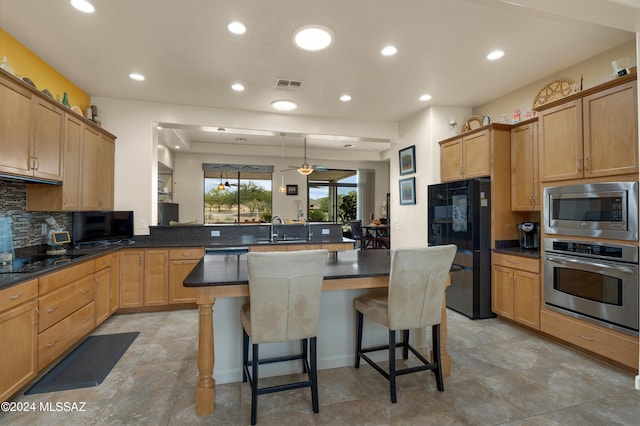 kitchen with a kitchen bar, a center island, kitchen peninsula, black appliances, and pendant lighting