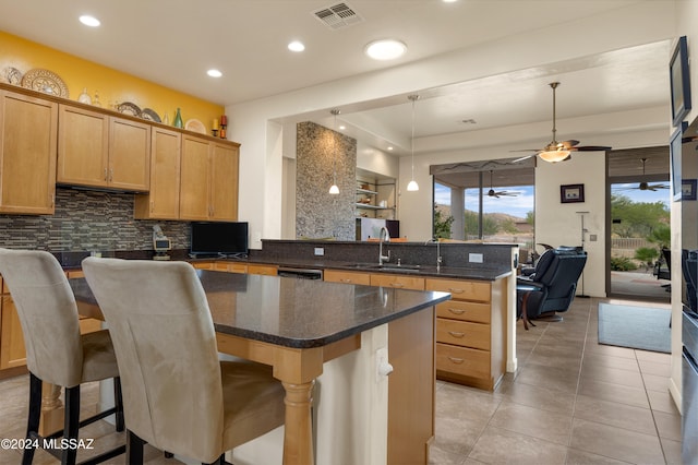 kitchen with sink, a breakfast bar, kitchen peninsula, tasteful backsplash, and ceiling fan