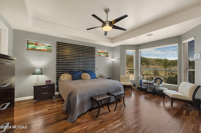 bedroom featuring dark hardwood / wood-style floors, ceiling fan, and a tray ceiling