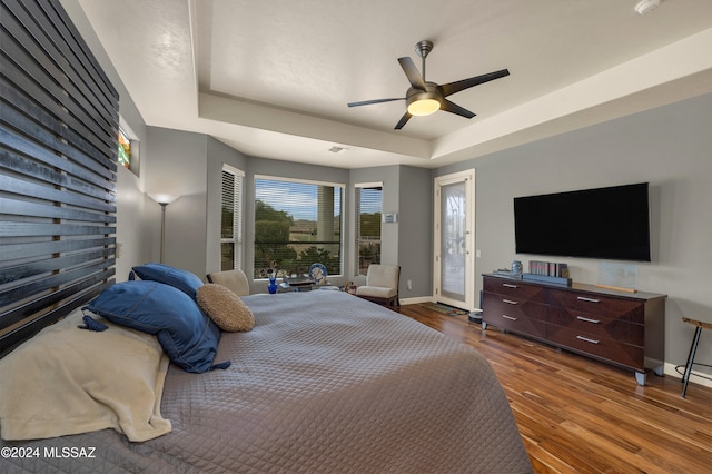 bedroom featuring a tray ceiling, wood-type flooring, and ceiling fan