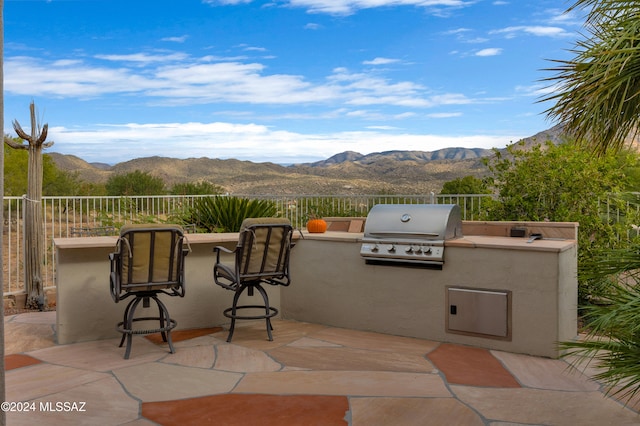 view of patio featuring exterior kitchen, a mountain view, exterior bar, and grilling area