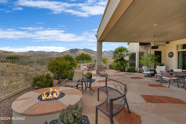 view of patio with a mountain view, a fire pit, and ceiling fan