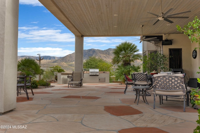 view of patio with exterior kitchen, a mountain view, ceiling fan, and area for grilling