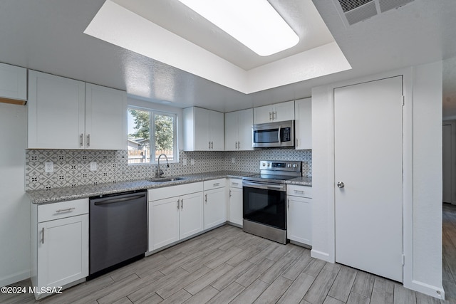 kitchen with light hardwood / wood-style flooring, appliances with stainless steel finishes, sink, and white cabinets