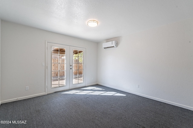 carpeted spare room featuring a wall unit AC, french doors, and a textured ceiling