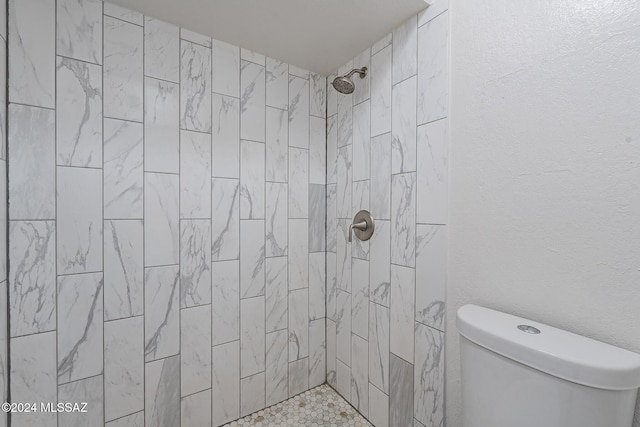 bathroom featuring tiled shower and toilet