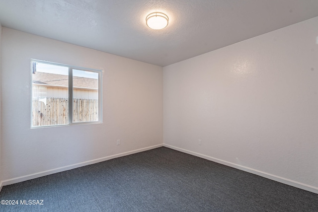 empty room with a textured ceiling and dark carpet