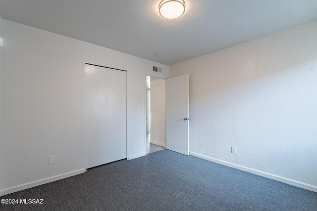 unfurnished bedroom featuring a closet and dark carpet