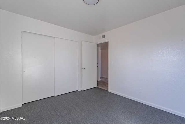 unfurnished bedroom with a closet and dark carpet