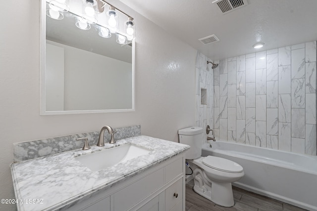 full bathroom featuring toilet, tiled shower / bath combo, a textured ceiling, hardwood / wood-style flooring, and vanity