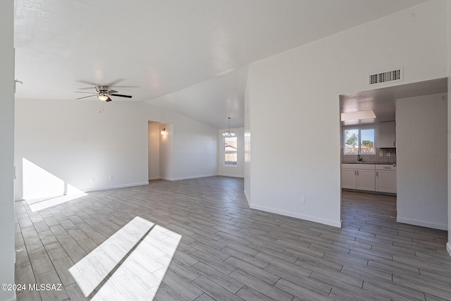 unfurnished living room with ceiling fan, lofted ceiling, sink, and light hardwood / wood-style floors