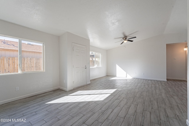 spare room featuring light hardwood / wood-style floors, ceiling fan, a textured ceiling, and lofted ceiling