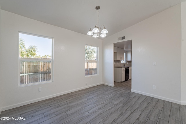 unfurnished room with light hardwood / wood-style floors, an inviting chandelier, and a healthy amount of sunlight