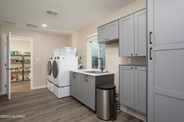 washroom with sink, independent washer and dryer, light hardwood / wood-style floors, and cabinets