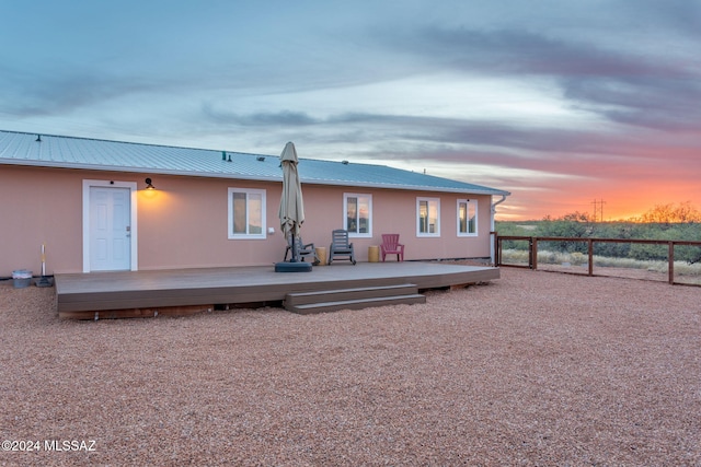 back house at dusk featuring a deck