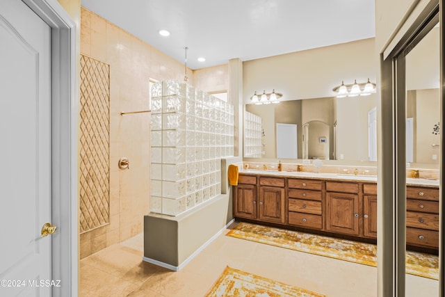 bathroom with a tile shower, tile patterned flooring, and vanity