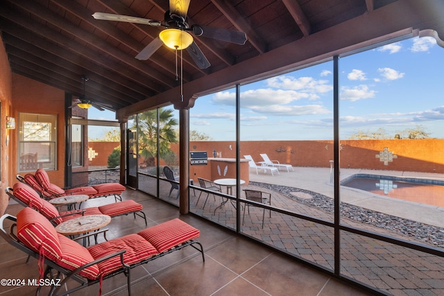 sunroom / solarium featuring lofted ceiling with beams, ceiling fan, and wooden ceiling