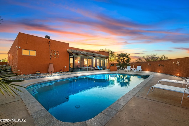 pool at dusk with a patio area