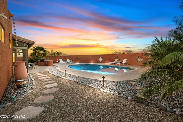 pool at dusk featuring a patio area