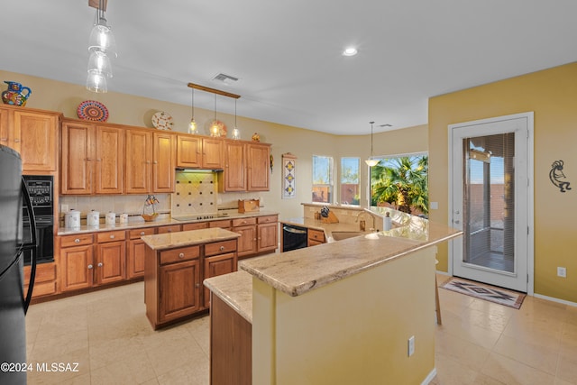 kitchen with pendant lighting, black appliances, sink, an island with sink, and tasteful backsplash