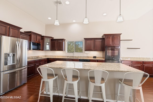 kitchen featuring sink, black appliances, dark hardwood / wood-style floors, decorative light fixtures, and a center island