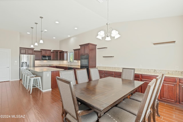 dining space with high vaulted ceiling, wood-type flooring, a chandelier, and sink