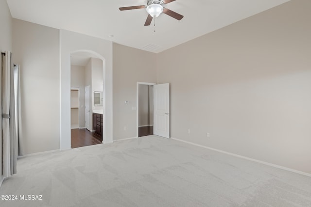 unfurnished bedroom featuring ensuite bath, carpet floors, ceiling fan, and a spacious closet