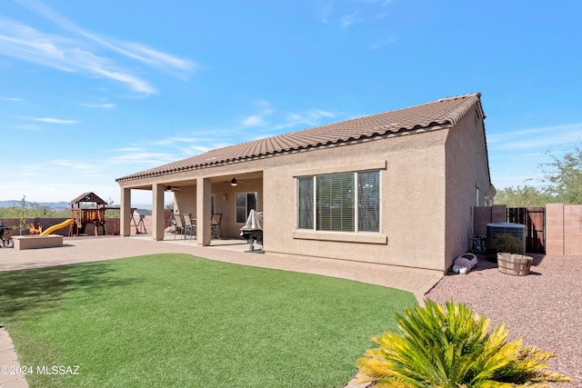 rear view of property with a playground, central air condition unit, a lawn, and a patio