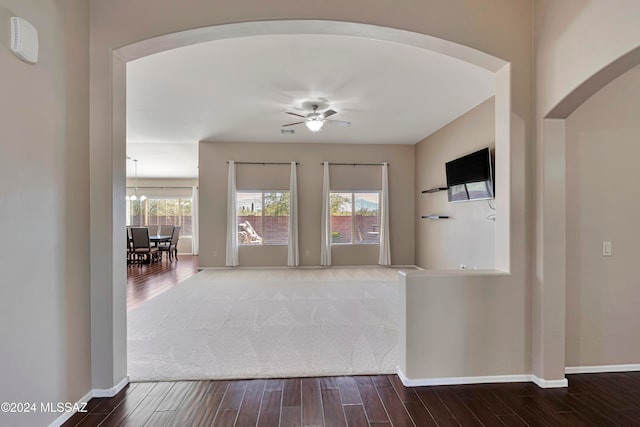 interior space with ceiling fan with notable chandelier and dark wood-type flooring