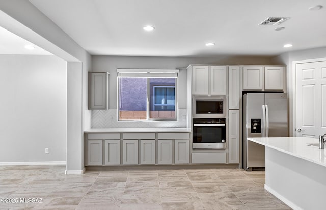 kitchen with tasteful backsplash, stainless steel appliances, and gray cabinetry