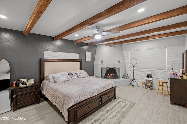 bedroom with ceiling fan, beam ceiling, and light wood-type flooring