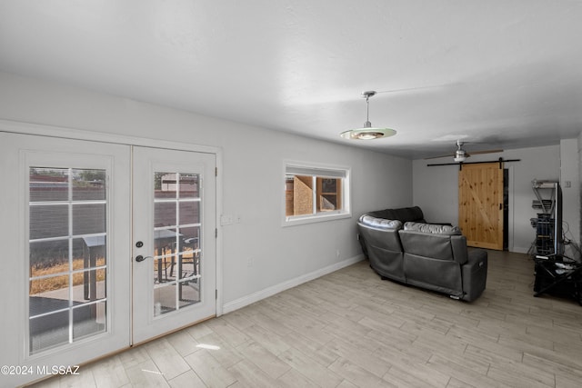 sitting room featuring light hardwood / wood-style floors, a barn door, french doors, and plenty of natural light