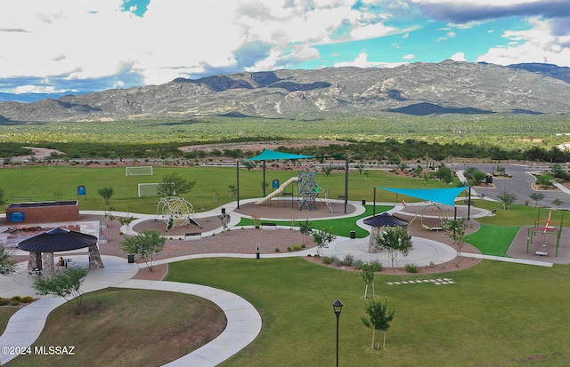 view of home's community with a mountain view, a lawn, and a playground