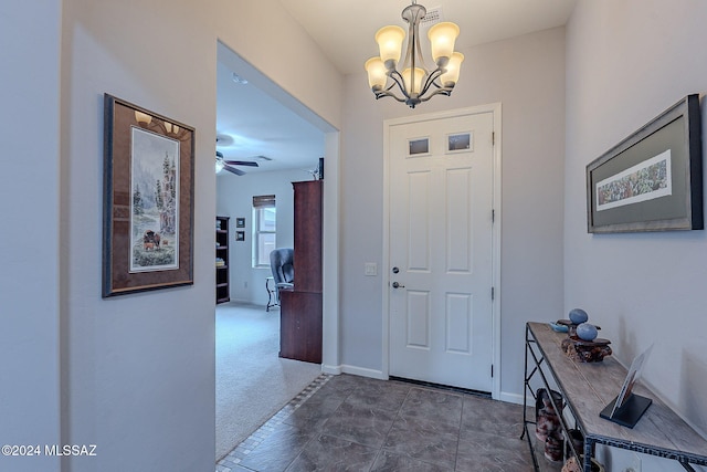 foyer featuring dark colored carpet and ceiling fan with notable chandelier