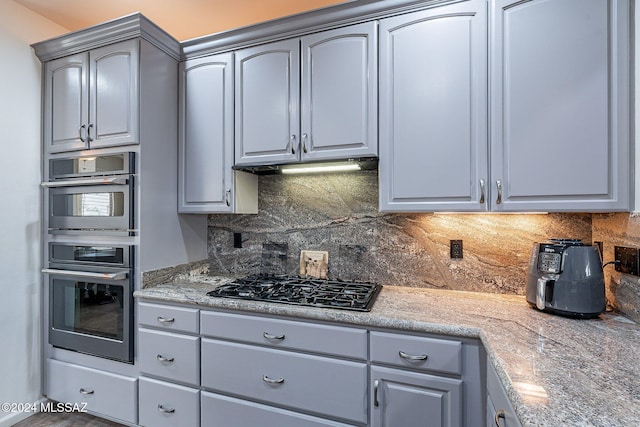 kitchen with gray cabinetry, black gas stovetop, backsplash, and double oven