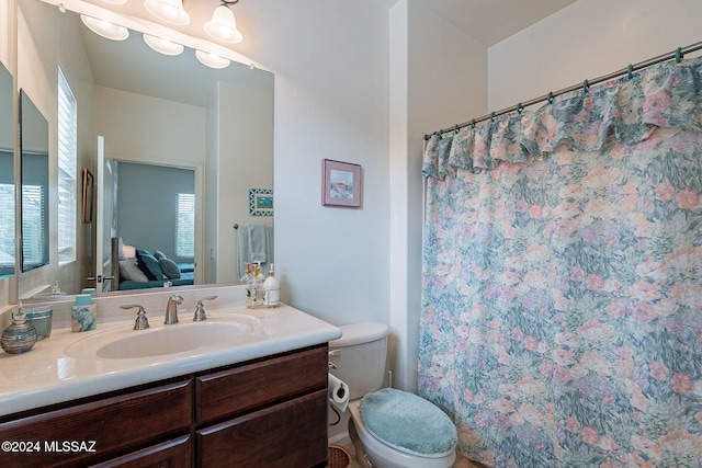 bathroom featuring a shower with shower curtain, vanity, and toilet