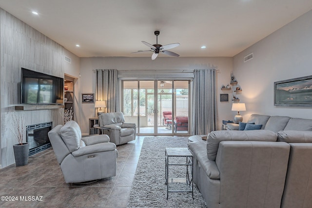 tiled living room with ceiling fan and a large fireplace